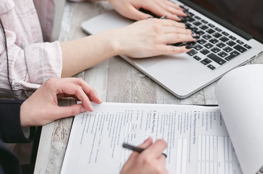 Completing a self assessment tax return online, checking paperwork against the figures entered on a laptop Completing a self assessment tax return online, checking paperwork against the figures entered on a laptop