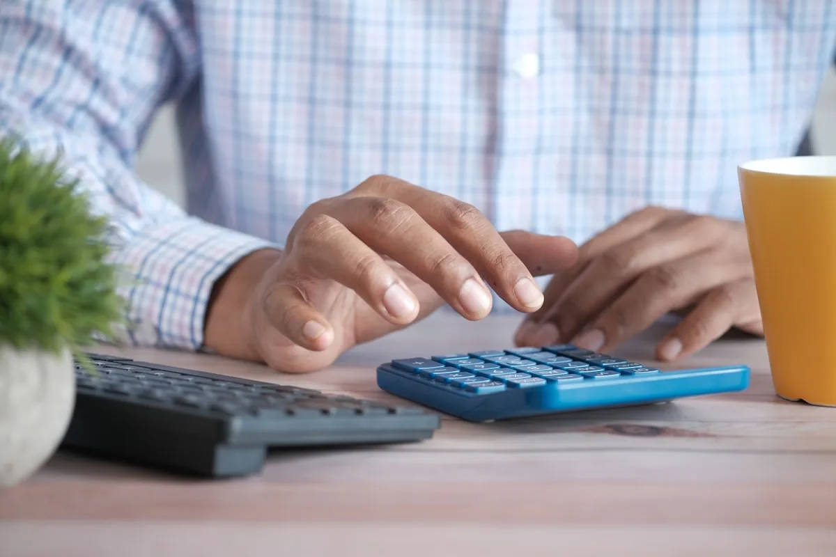 A UK sole trader comparing cash basis and traditional accounting at a desk with invoices and a laptop