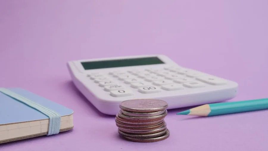 Working out the cost of an accountant with a calculator, stacked coins and a notepad Working out the cost of an accountant with a calculator, stacked coins and a notepad