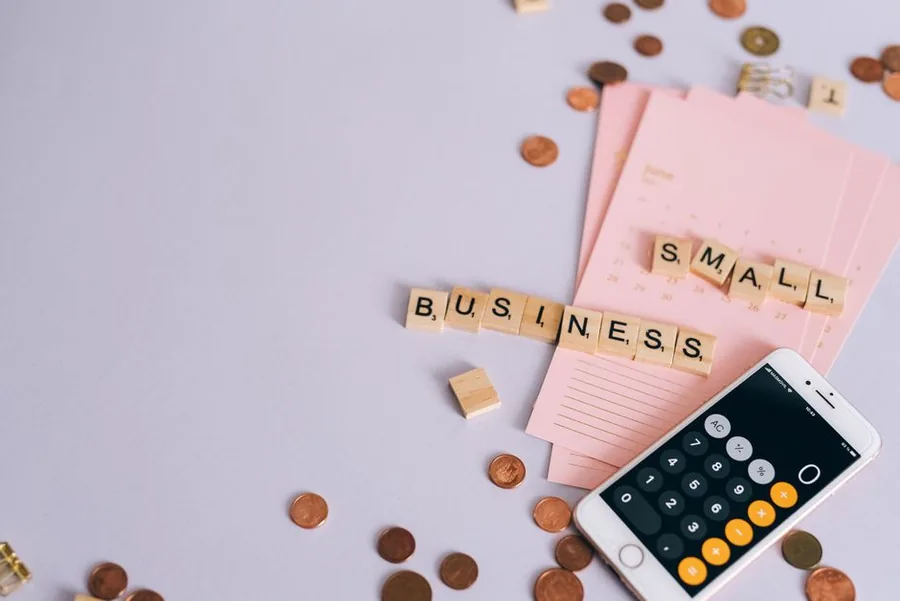 Totting up childminding start up costs and pre-trading expenses with a calculator, coins and notes