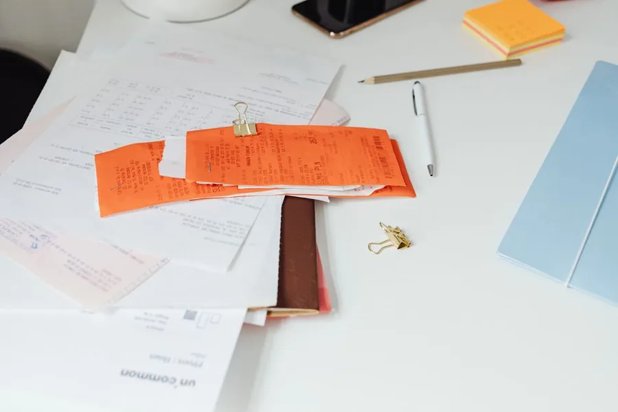 A childminder sorting receipts and paperwork on a desk to total up allowable business expenses A childminder sorting receipts and paperwork on a desk to total up allowable business expenses