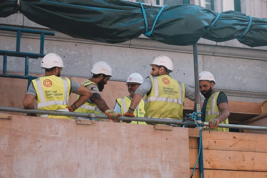 A team of UK builders in hi-vis vests and hard hats working on a scaffolded site, the kind of crew that needs public liability cover A team of UK builders in hi-vis vests and hard hats working on a scaffolded site, the kind of crew that needs public liability cover
