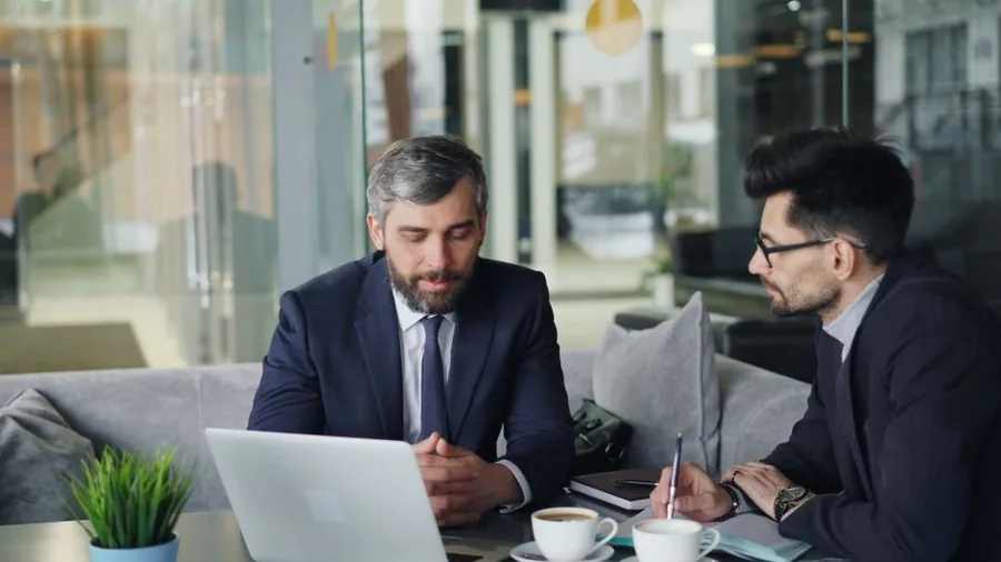 A UK consultant reviewing figures on a laptop with an adviser while weighing up sole trader against limited company A UK consultant reviewing figures on a laptop with an adviser while weighing up sole trader against limited company
