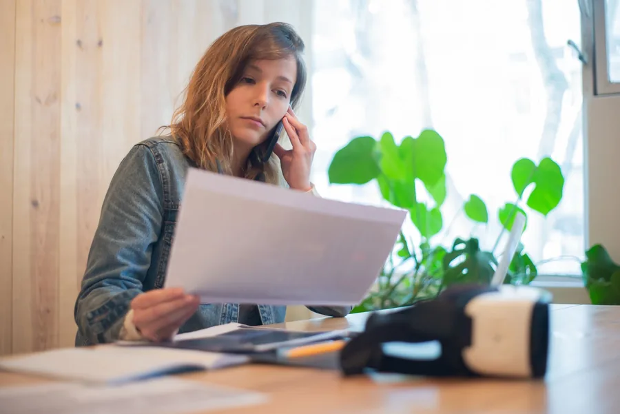 A small business owner on the phone while reviewing paperwork about a Corporation Tax penalty at a desk A small business owner on the phone while reviewing paperwork about a Corporation Tax penalty at a desk