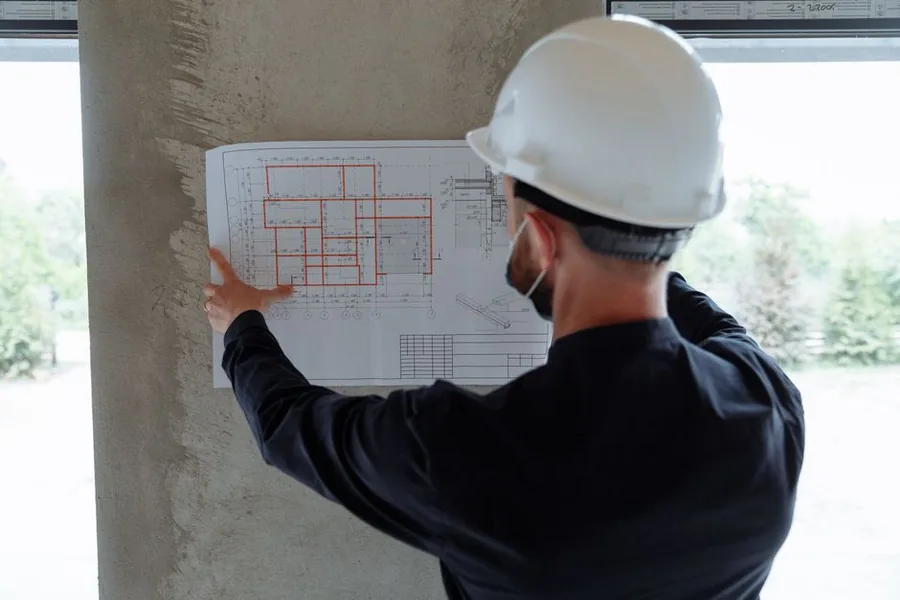 A site manager reviewing construction drawings on a project that could trigger the CIS deemed contractor threshold