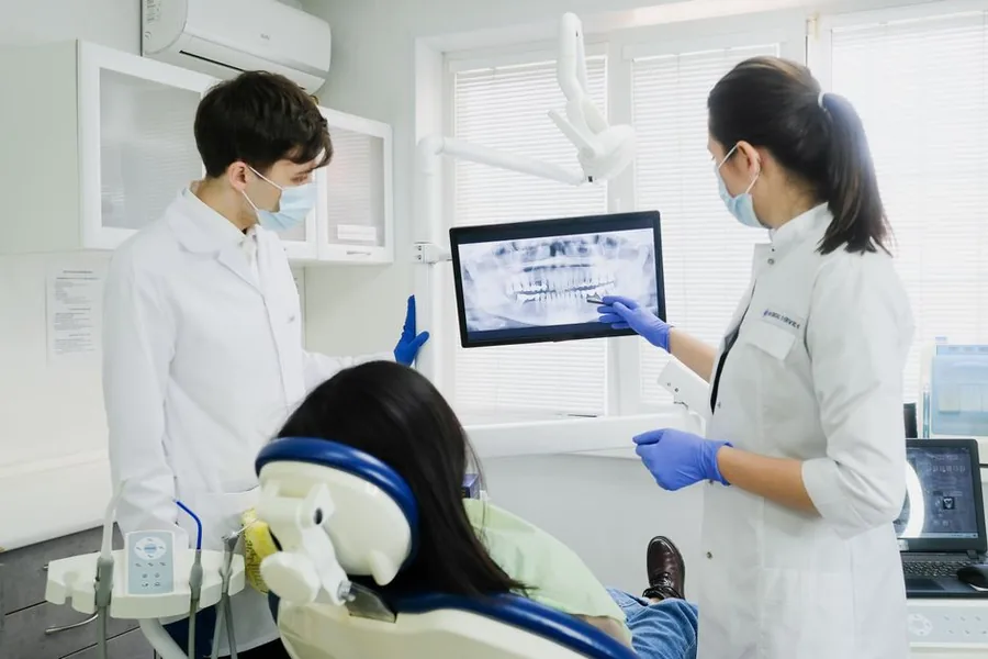 Dental practice staff reviewing notes on a tablet chairside with a patient during an appointment