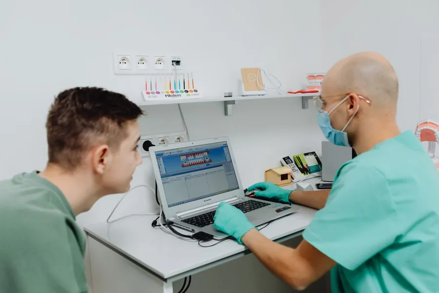 A dentist working at a practice desk computer, handling the admin and record keeping behind mileage and use of home claims A dentist working at a practice desk computer, handling the admin and record keeping behind mileage and use of home claims