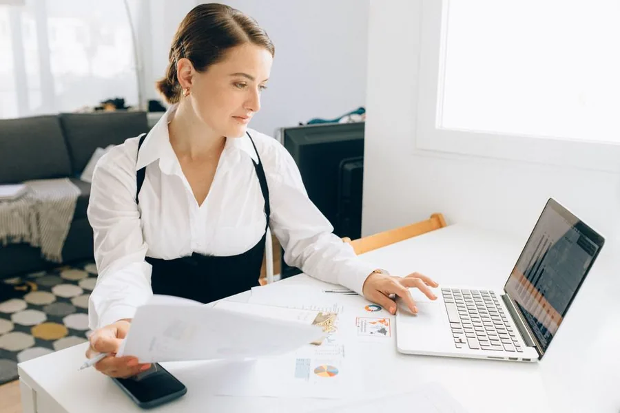 A company director reviewing pay figures and pie charts on a laptop to work out the best dividend and salary split