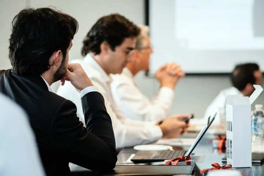 Company directors deliberating around the boardroom table over how to split profit between shareholders
