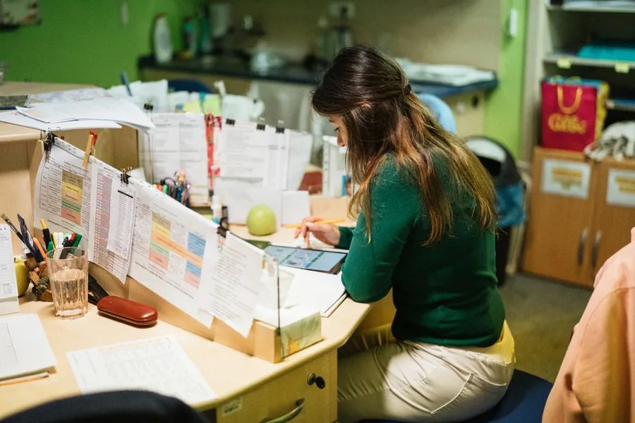A childminder working through her income and expense records at a nursery desk to keep on top of her tax return A childminder working through her income and expense records at a nursery desk to keep on top of her tax return
