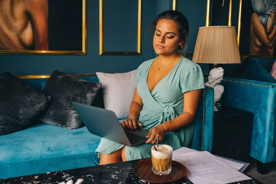 A freelancer working on her laptop with paperwork beside her, sorting out the tax on her second income A freelancer working on her laptop with paperwork beside her, sorting out the tax on her second income