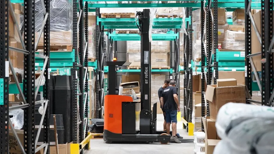 A reach truck moving stock through the racking of an ecommerce fulfilment warehouse A reach truck moving stock through the racking of an ecommerce fulfilment warehouse
