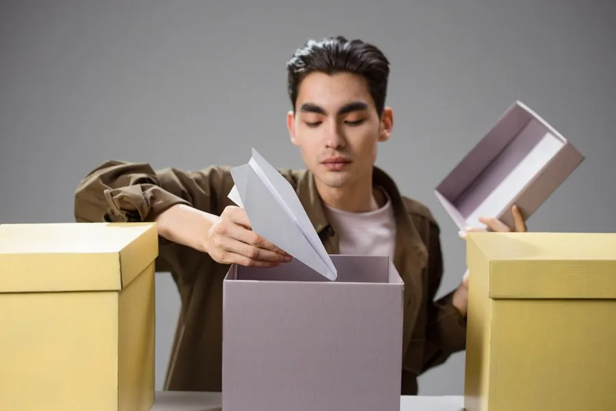 A UK ecommerce seller packing orders at a home desk, laptop open beside stacked parcels ready to post