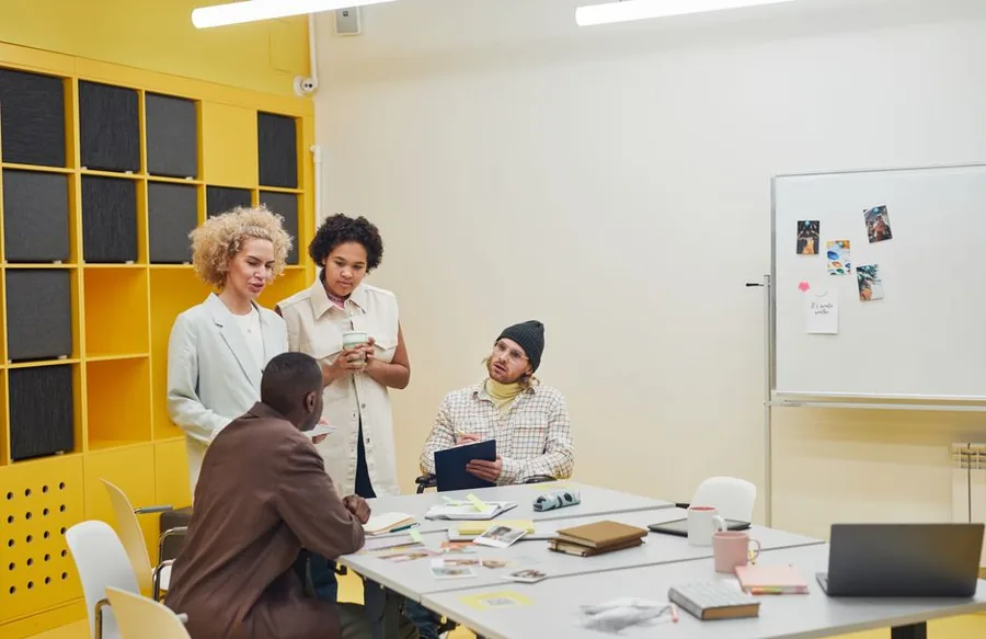 A startup team gathered around a table in a bright office, the kind of employees an EMI share option scheme is designed to reward A startup team gathered around a table in a bright office, the kind of employees an EMI share option scheme is designed to reward