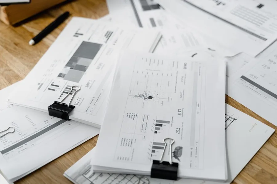 Payroll cost and financial analysis reports spread across a desk as an employer reviews staffing overheads
