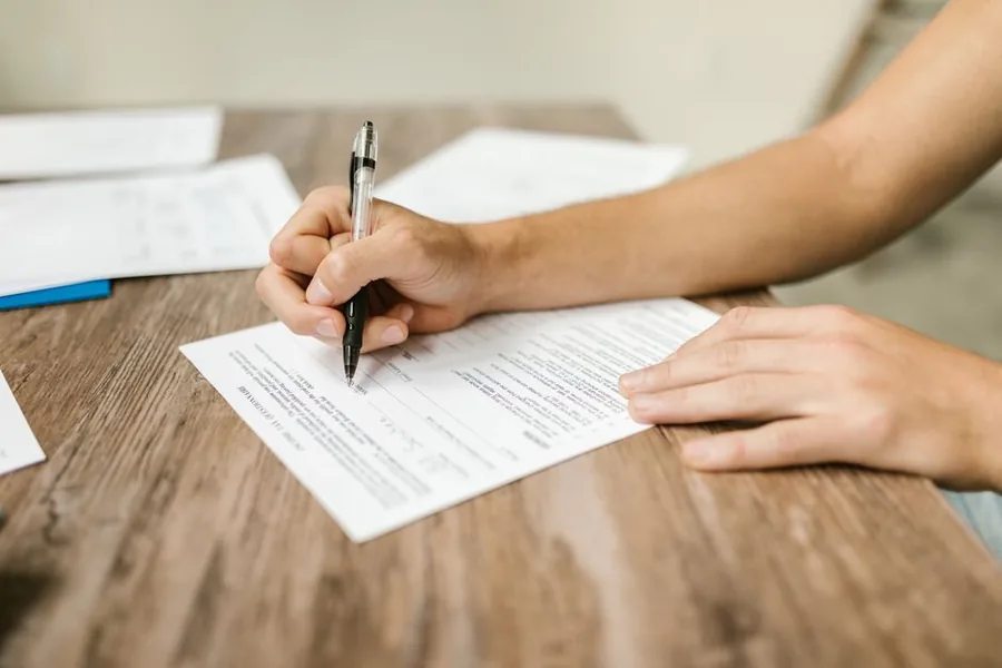 A sole trader completing a Self Assessment tax return by hand at a desk A sole trader completing a Self Assessment tax return by hand at a desk
