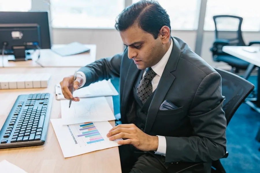 A finance leader reviewing company performance charts at a desk, weighing the value a CFO brings to a growing business A finance leader reviewing company performance charts at a desk, weighing the value a CFO brings to a growing business