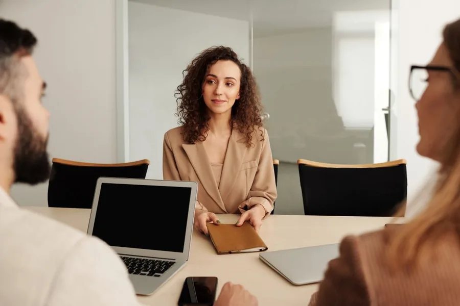 A jobseeker sitting across the table from two managers during a first-hire interview in a bright office A jobseeker sitting across the table from two managers during a first-hire interview in a bright office