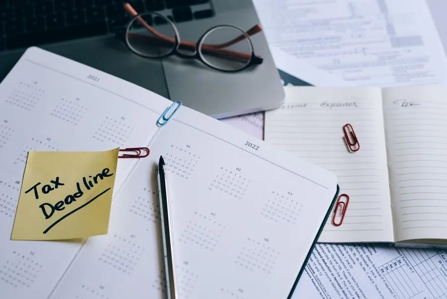 A tax deadline reminder note clipped to a calendar beside reading glasses and a laptop, cueing the risk of missing an HMRC payment date A tax deadline reminder note clipped to a calendar beside reading glasses and a laptop, cueing the risk of missing an HMRC payment date