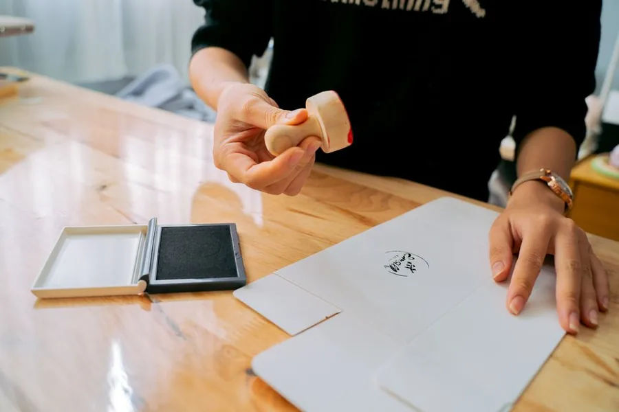 An online marketplace seller stamping and packing a parcel to post to a buyer on Vinted, eBay or Etsy