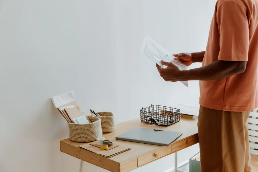 Small business owner sorting paperwork beside a closed laptop and coffee at a tidy desk, organising receipts and records digitally Small business owner sorting paperwork beside a closed laptop and coffee at a tidy desk, organising receipts and records digitally
