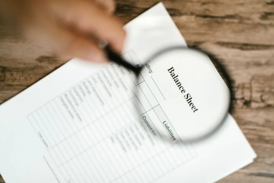 A company balance sheet examined under a magnifying glass while reviewing accounts for allowable corporation tax reliefs