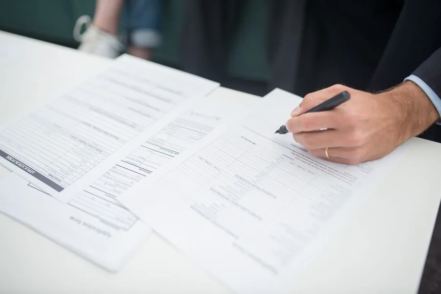 A business owner completing employer registration forms by hand before enrolling for PAYE with HMRC A business owner completing employer registration forms by hand before enrolling for PAYE with HMRC