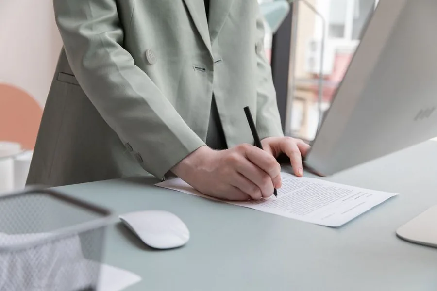 A company director signing a Companies House restoration application at an office desk A company director signing a Companies House restoration application at an office desk