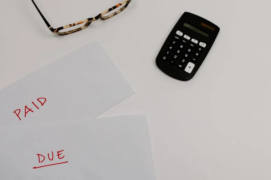 Envelopes marked paid and due beside a calculator, sorting which tax bills have cleared and which are still outstanding Envelopes marked paid and due beside a calculator, sorting which tax bills have cleared and which are still outstanding