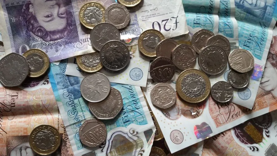 A spread of British banknotes and coins representing income tax owed on UK earnings A spread of British banknotes and coins representing income tax owed on UK earnings