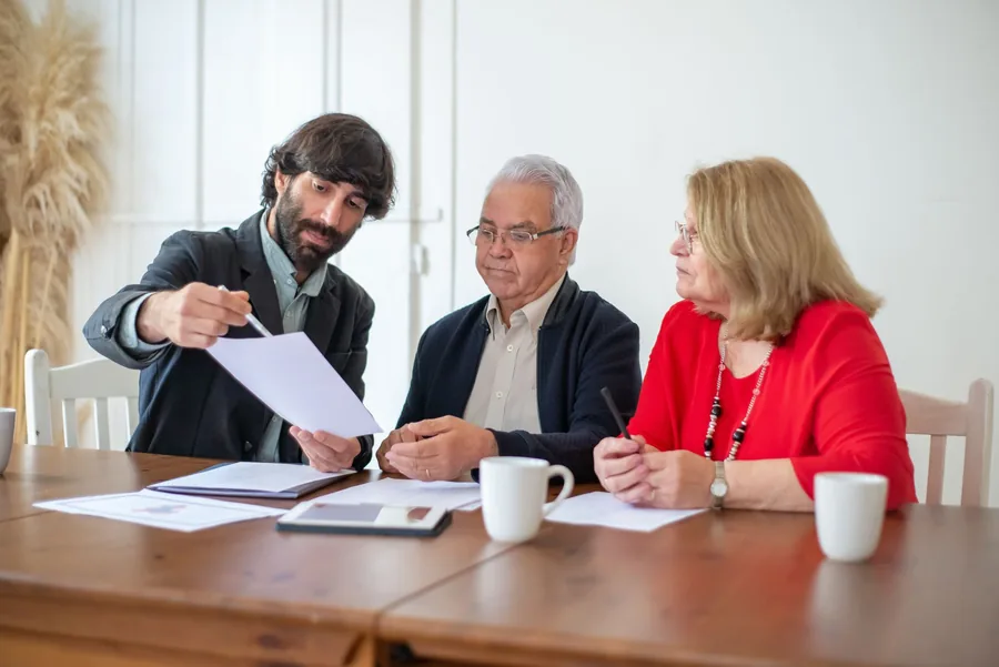 An older couple reviewing their estate and lifetime gifting plans with a financial adviser at a table An older couple reviewing their estate and lifetime gifting plans with a financial adviser at a table