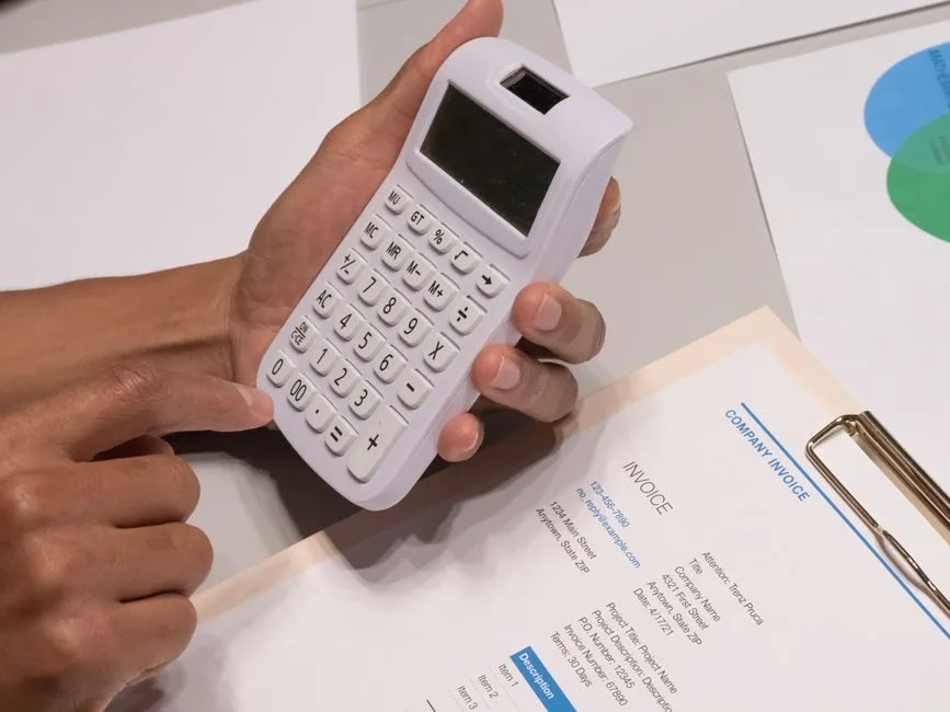 A business owner checking a printed UK invoice showing a £150 total before issuing it to a client A business owner checking a printed UK invoice showing a £150 total before issuing it to a client