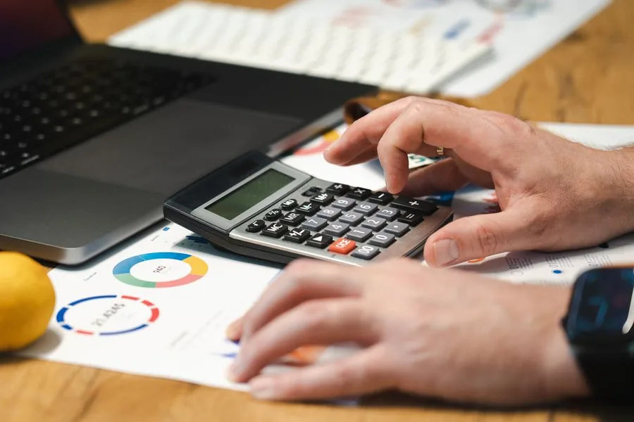 Checking payroll figures on a calculator against financial statements to confirm the right tax code