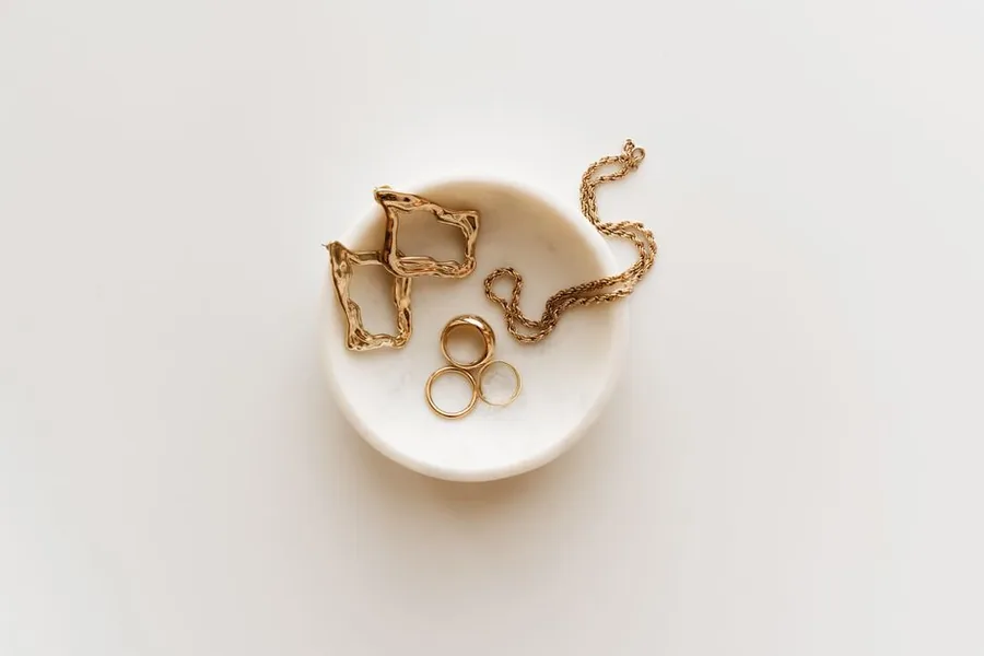 Finished gold rings, earrings and a chain laid out on a marble dish, the trading stock a UK jewellery business records in its accounts