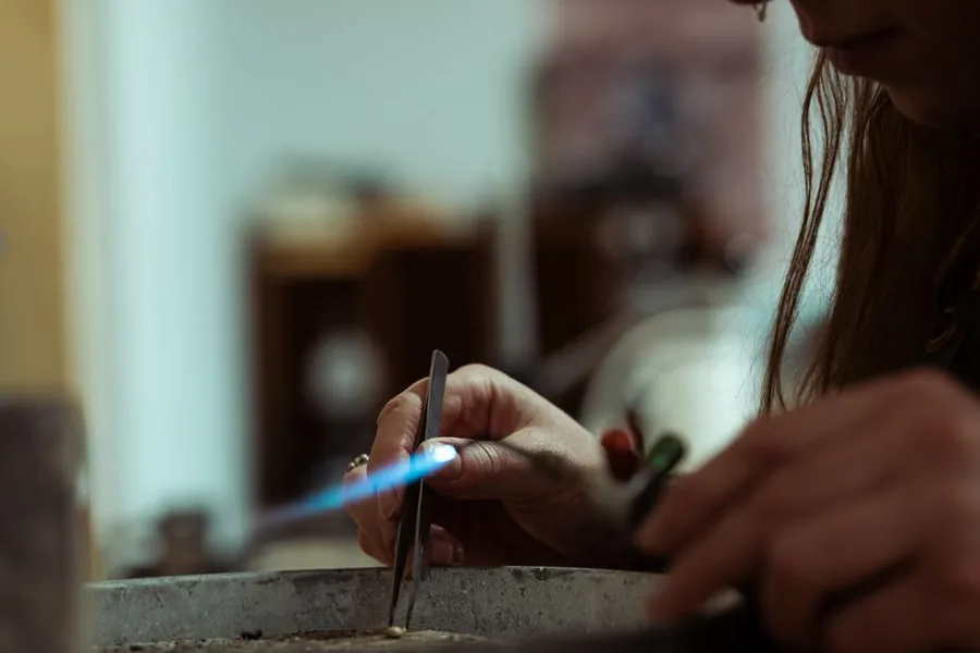 A jeweller soldering a piece at the workbench, the kind of unfinished stock a work in progress valuation captures A jeweller soldering a piece at the workbench, the kind of unfinished stock a work in progress valuation captures