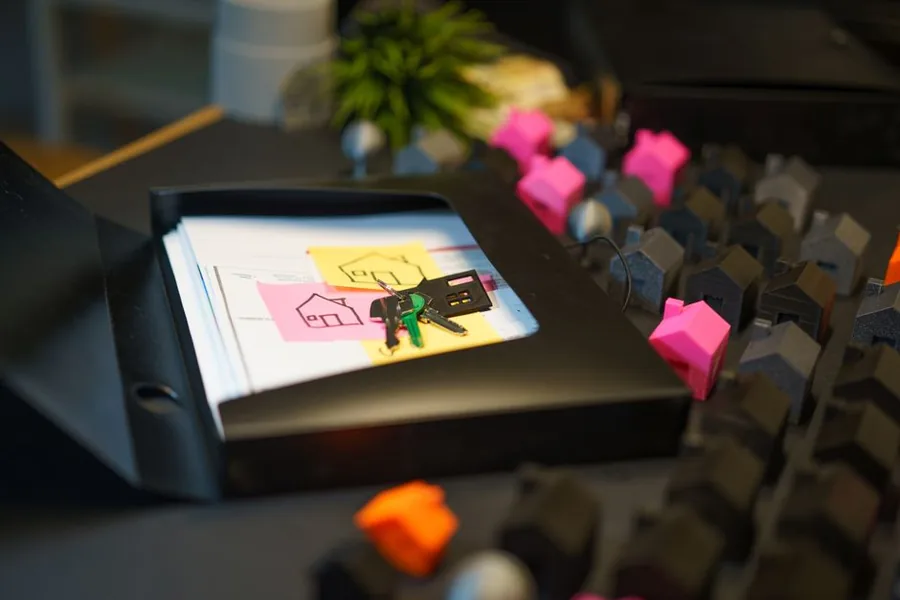 A landlord's rental paperwork and keys filed in a binder beside model houses, ready for logging allowable expenses A landlord's rental paperwork and keys filed in a binder beside model houses, ready for logging allowable expenses