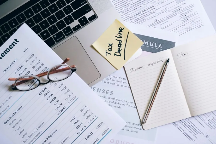 A landlord's desk with a tax deadline reminder, an income and expenses notebook and financial statements ready for a self assessment return A landlord's desk with a tax deadline reminder, an income and expenses notebook and financial statements ready for a self assessment return