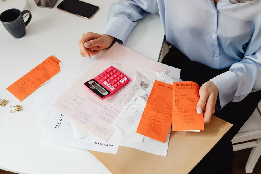 A company director sorting business receipts with a calculator to work out which costs are allowable expenses