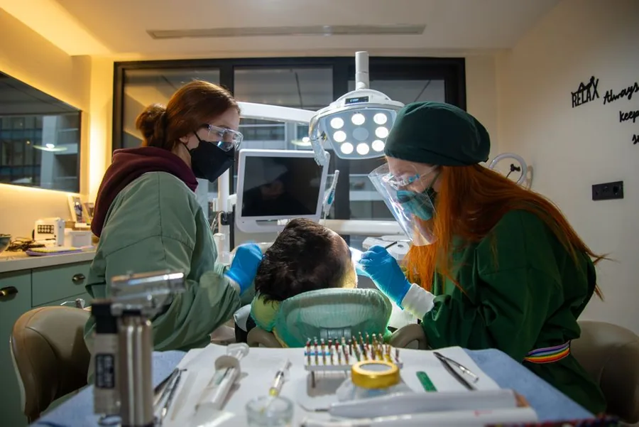 Two dentists treating a patient in a modern UK dental surgery, the kind of practice a locum dentist works across Two dentists treating a patient in a modern UK dental surgery, the kind of practice a locum dentist works across