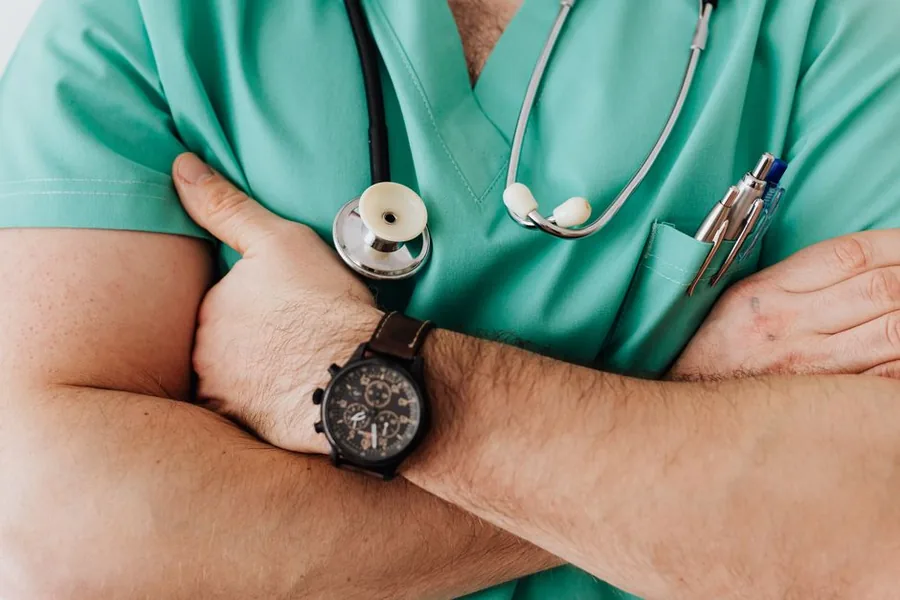 A locum doctor in green scrubs with arms folded, weighing up whether to work through a limited company