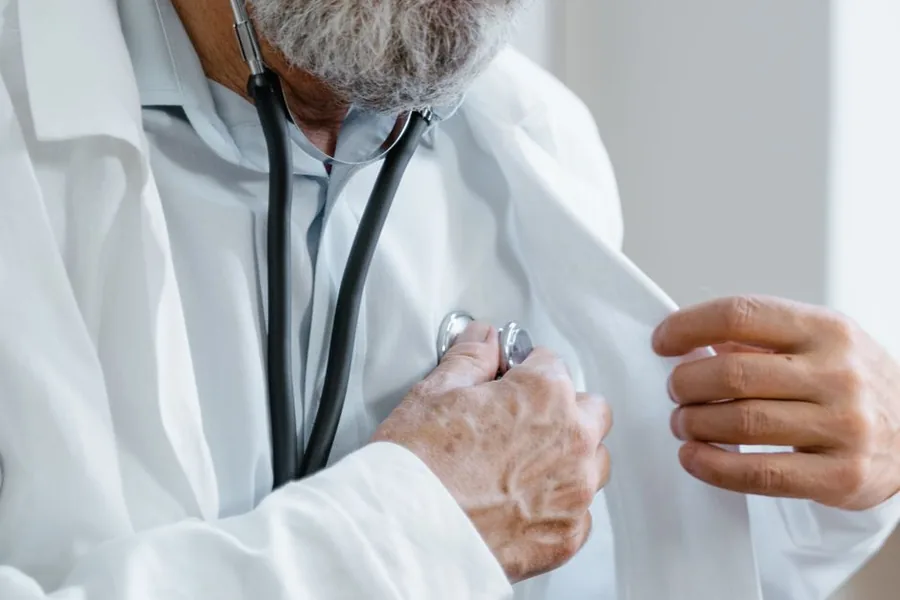 A senior GP in a white coat with a stethoscope, representing locum doctors tracking NHS pensionable pay