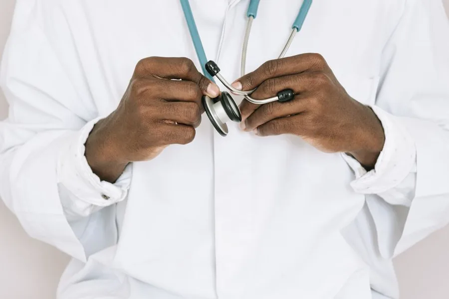 A locum GP in a white coat preparing a stethoscope, the kind of clinician who completes NHS Pension Forms A and B A locum GP in a white coat preparing a stethoscope, the kind of clinician who completes NHS Pension Forms A and B