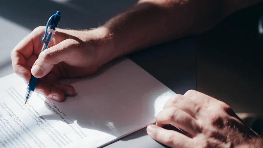 Completing a paper form by hand, the kind of official paperwork where your National Insurance number is often recorded Completing a paper form by hand, the kind of official paperwork where your National Insurance number is often recorded