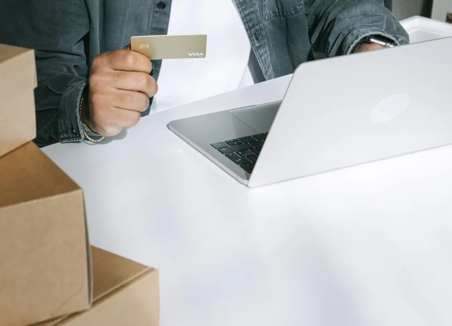An online seller boxing up orders and paying at a laptop, the kind of limited company that needs the right business insurance cover An online seller boxing up orders and paying at a laptop, the kind of limited company that needs the right business insurance cover