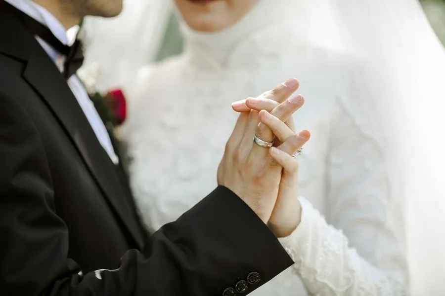 A newly married couple hold hands wearing their wedding rings, the moment that unlocks a marriage tax allowance claim