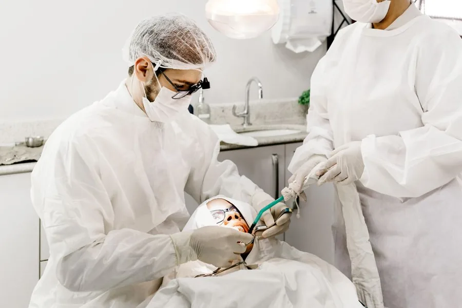 A dentist and assistant treating a patient in a modern surgery, the kind of NHS clinician affected by the McCloud pension remedy