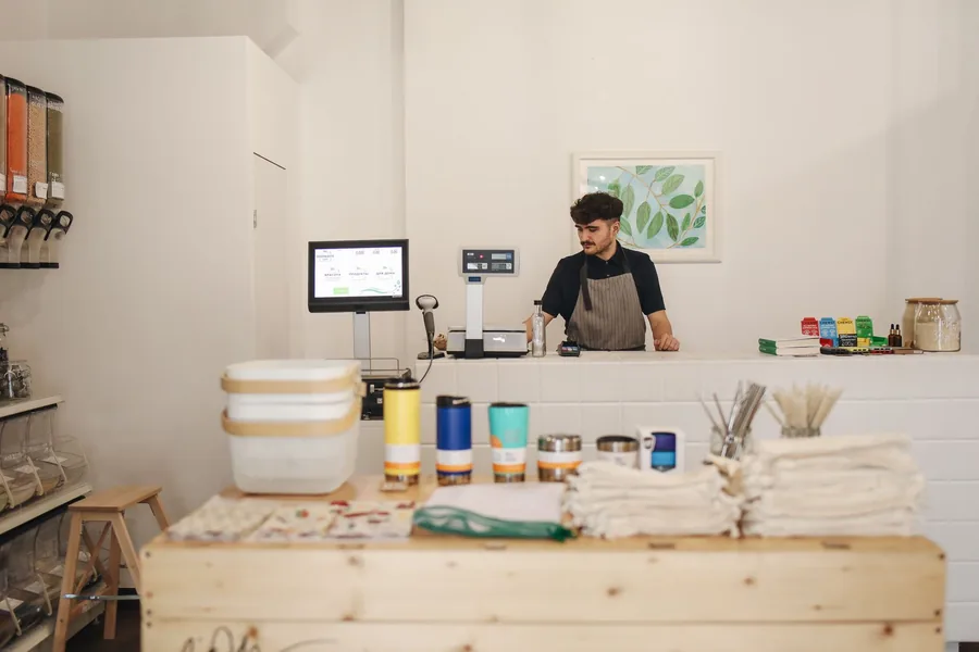 A shop assistant working behind the counter of an independent UK store, one of the roles covered by the National Minimum Wage A shop assistant working behind the counter of an independent UK store, one of the roles covered by the National Minimum Wage