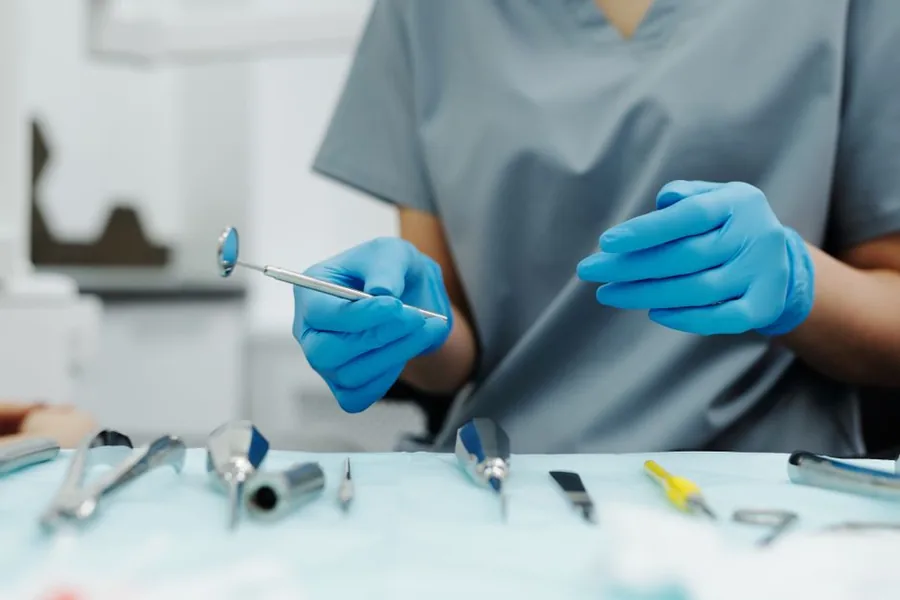 A UK dentist in scrubs preparing instruments at the chairside in a mixed NHS and private practice A UK dentist in scrubs preparing instruments at the chairside in a mixed NHS and private practice