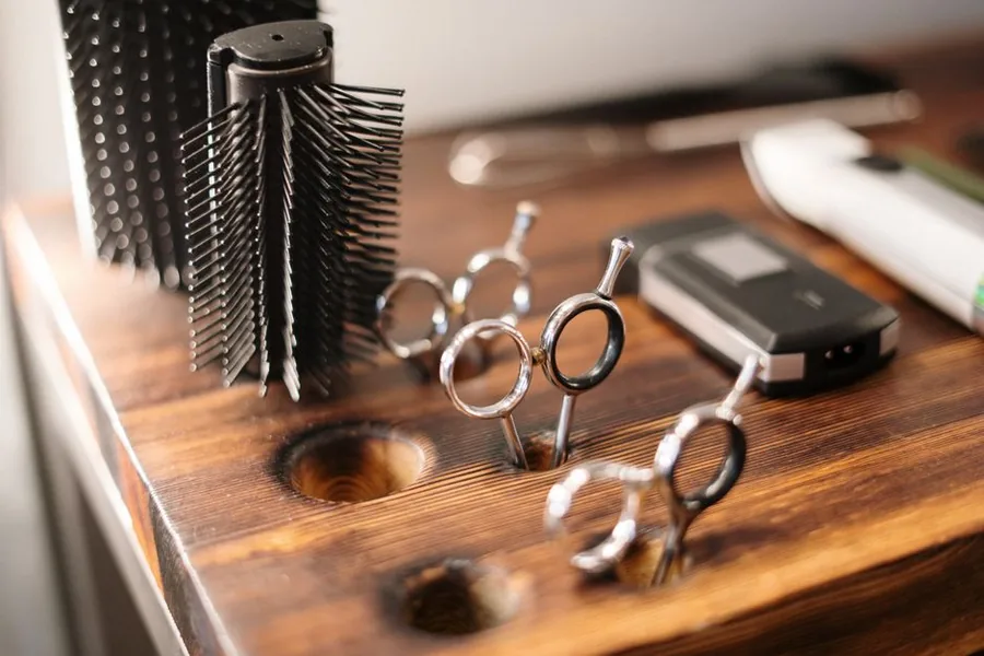 A mobile hairdresser's scissors, round brush and clippers laid out on a wooden worktop ready for home visits A mobile hairdresser's scissors, round brush and clippers laid out on a wooden worktop ready for home visits