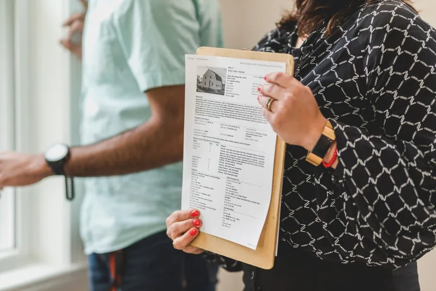 A landlord reviewing property portfolio paperwork with a colleague while sorting details for several rental properties A landlord reviewing property portfolio paperwork with a colleague while sorting details for several rental properties
